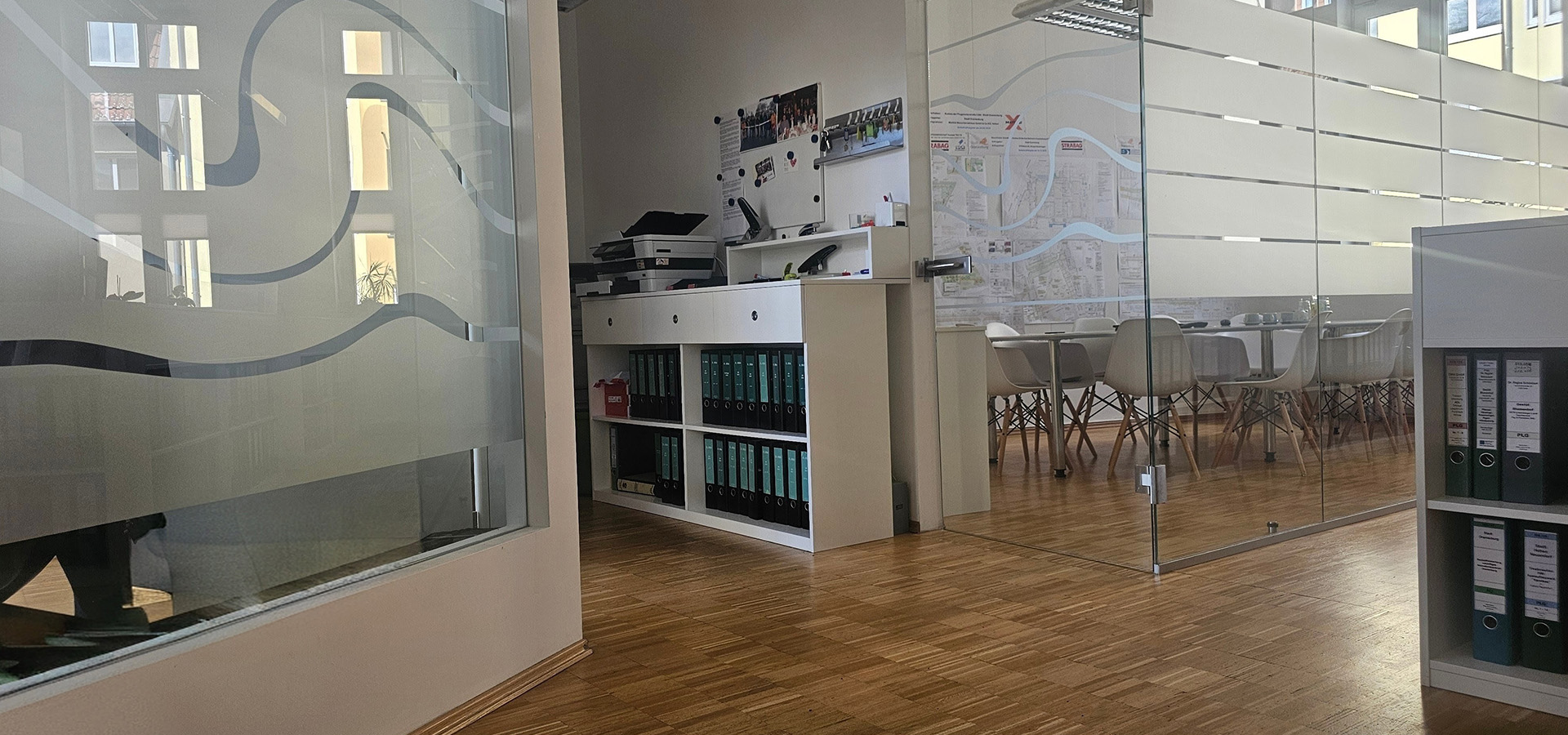 Leeres Büro mit Glaswänden, Holzboden und Ordnerregalen in Grau