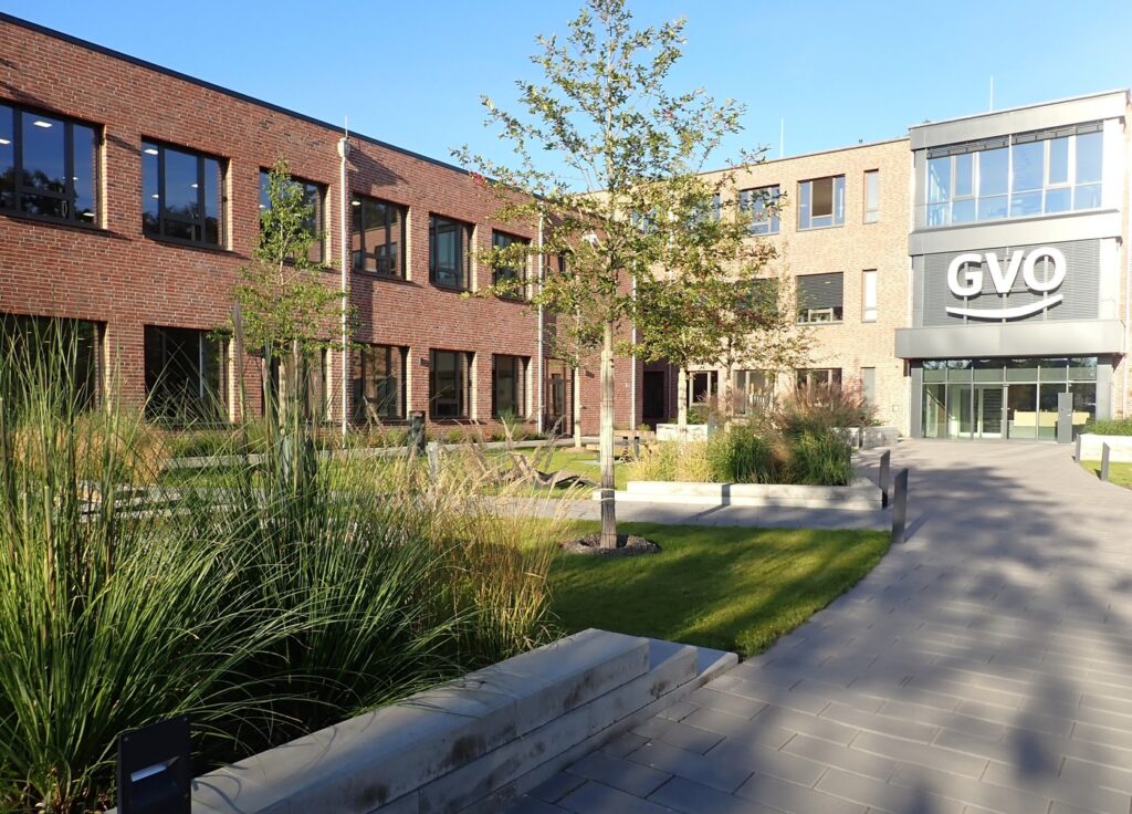 Moderner GVO Buerokomplex aus Backstein und Glas mit Gruenanlage