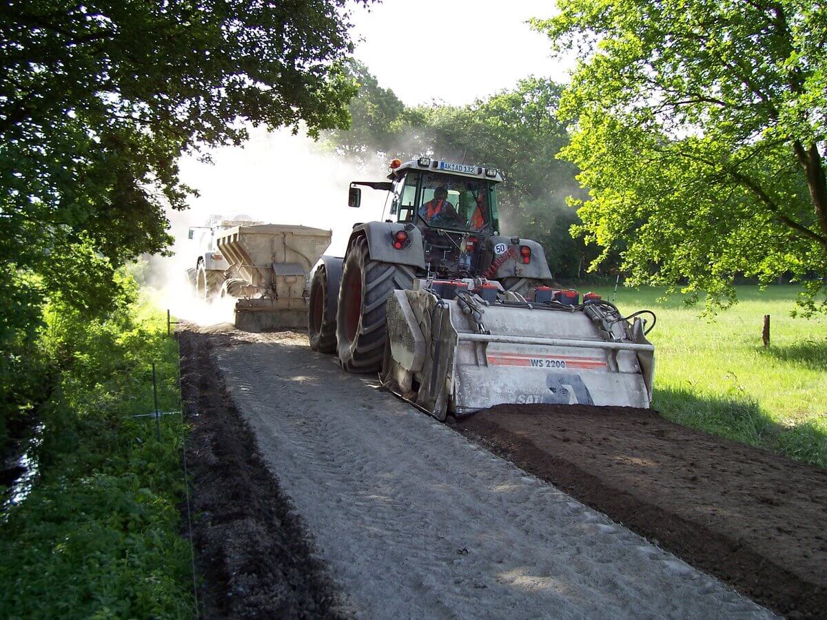 Traktorfahrer konzentriert auf grauem Traktor, Staub und Fräse im Grün