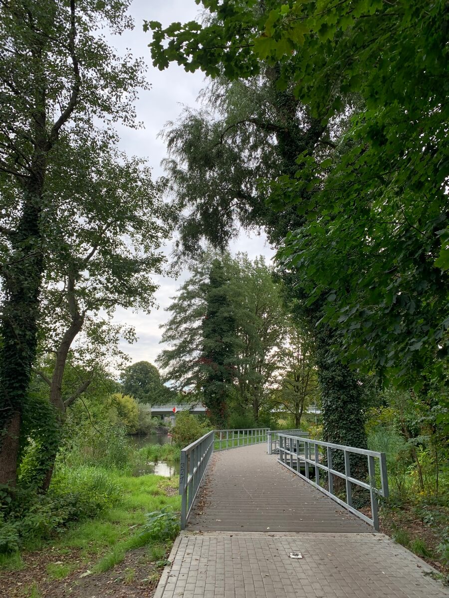 Ruhiger Parkweg mit grauer Bruecke im Gruen, interessante Gelaender