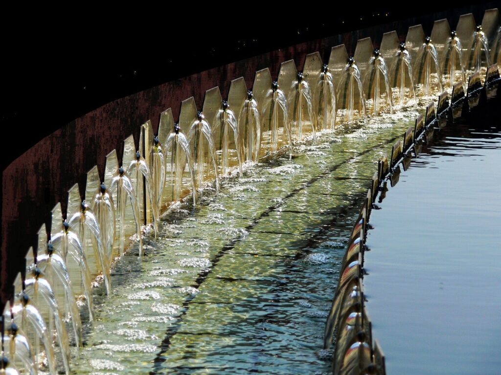 Goldene Wasserboegen am Brunnenrand mit blauem Becken und Glanz