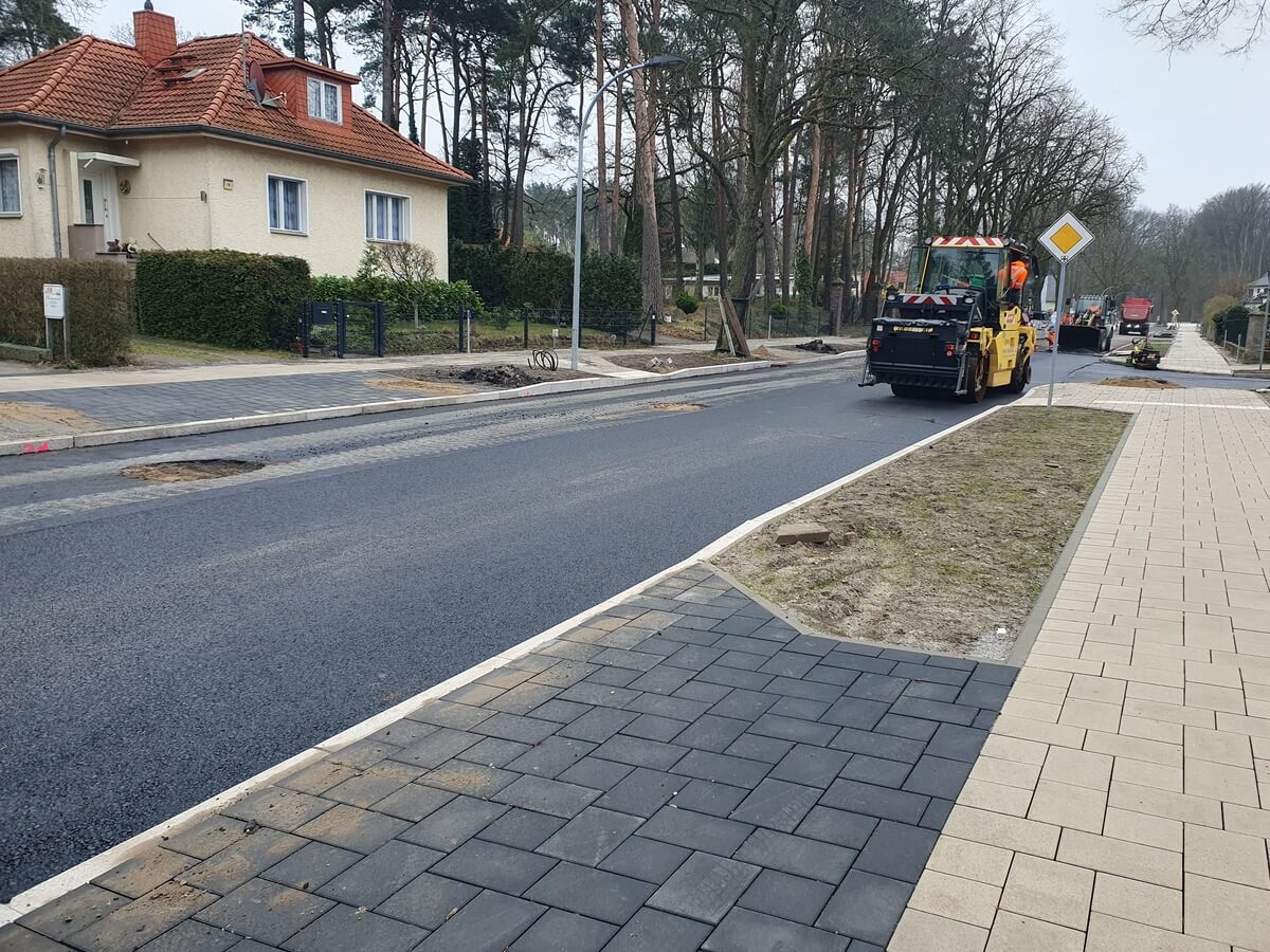 Schwarze Straßenwalze ohne Gesicht, dunkler Asphalt, Baustelle am Rand