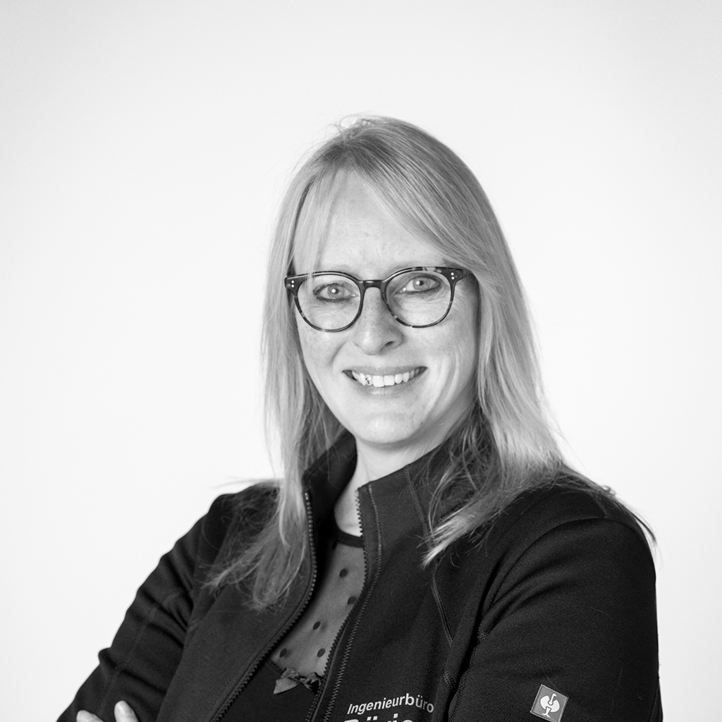 Laechelnde Frau mit blonden Haaren und Brille in dunkler Jacke
